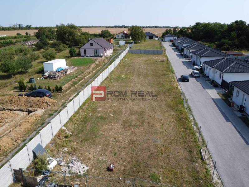 Stavebný pozemok so stavebným povolením a projektom na dvojdom - Pozemky - bývanie v Štefanovej, vedľa prázdna parcela, obklopené vidieckymi domami a zeleňou.