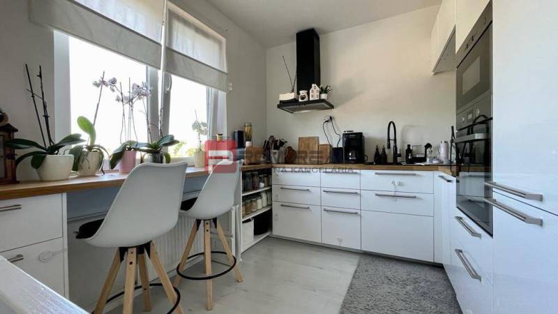 Na PREDAJ priestranný 3 izbový byt s balkónom v meste Senec - Kuchyňa v 3-izbovom byte s bielymi skrinkami a barovými stoličkami.