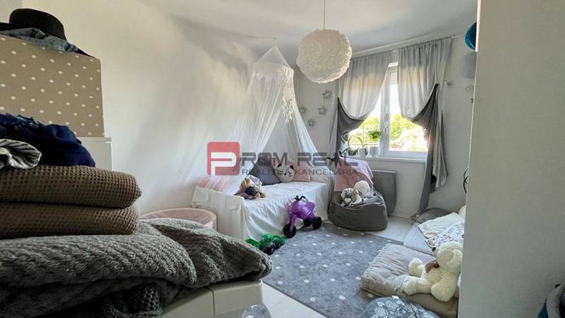 Na PREDAJ priestranný 3 izbový byt s balkónom v meste Senec - Detská izba v 3-izbovom byte s hračkami a posteľou, s výhľadom cez záclony.