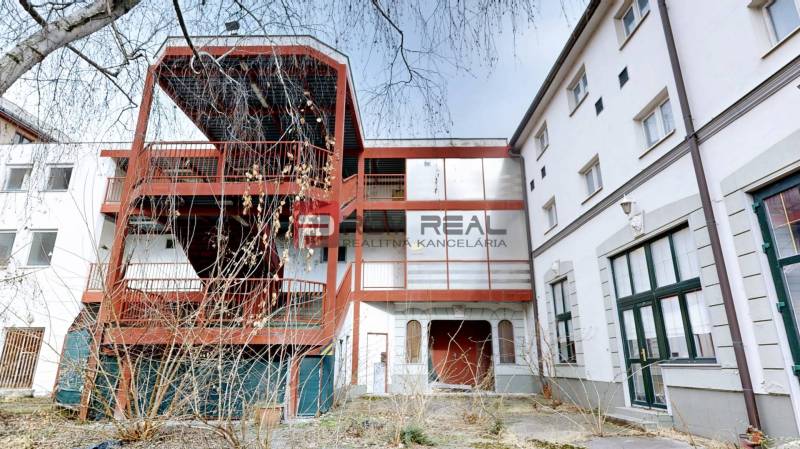 EXKLUZÍVNA INVESTÍCIA: MULTIFUNKČNÁ BUDOVA NA PREDAJ, TRNAVA - Budova na ulici Ľ. Podjavorinskej v Trnave s exteriérovým kovovým schodiskom a presklenými oknami.