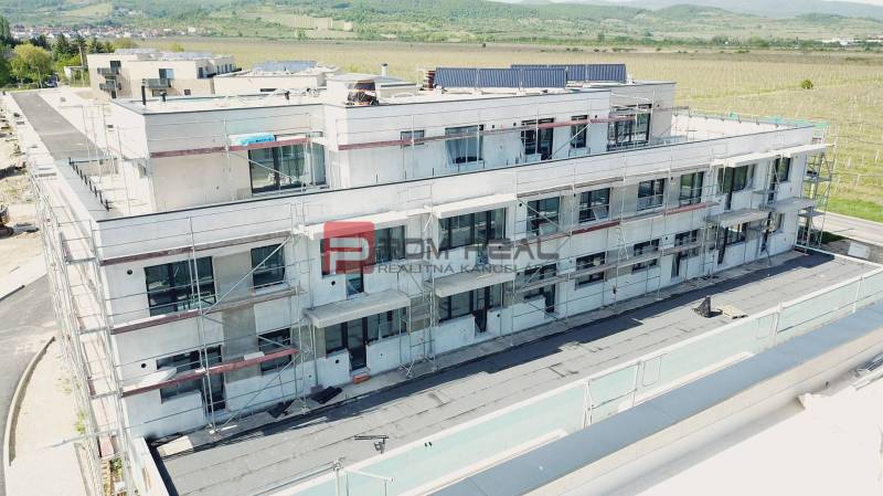 PREDAJ 3i byt, 86 m2, Prémiová novost. Zelené Nivy, Pezinok - Budova na Limbašskej ceste v Pezinku, ktorá je vo výstavbe, s výhľadom na okolie.