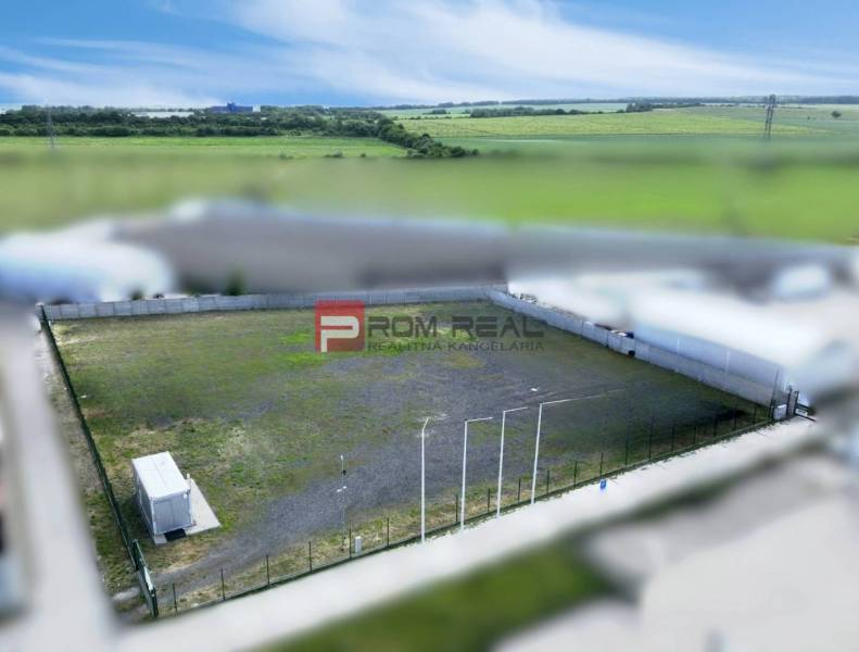 Prenájom spevnenej plochy - parking, skladovanie, Pezinok - Výrobné priestory v Pezinku s oploteným vonkajším priestorom a kontajnerom, obklopené poľami.