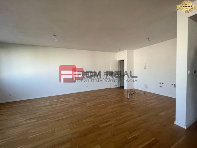 NA Predaj 4 izbový byt v projekte VINICE Pezinok 150m2 - Priestranný interiér 4-izbového bytu s drevenou podlahou a bielymi stenami.