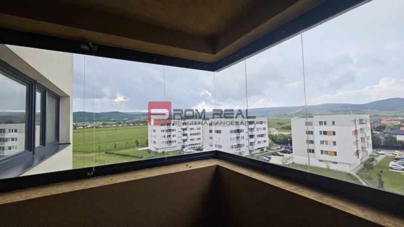 NA Predaj 4 izbový byt v projekte VINICE Pezinok 150m2 - Výhľad z balkóna 4-izbového bytu na zelené polia a okolité budovy v Pezinku.