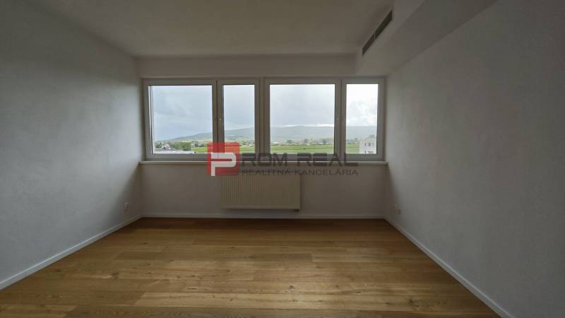NA Predaj 4 izbový byt v projekte VINICE Pezinok 150m2 - Priestranná miestnosť so svetlými stenami a drevenou podlahou v 4-izbovom byte.