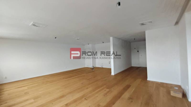 NA Predaj 4 izbový byt v projekte VINICE Pezinok 150m2 - Priestranná miestnosť s drevenou podlahou v 4-izbovom byte, svetlé steny a jednoduché zariadenie.