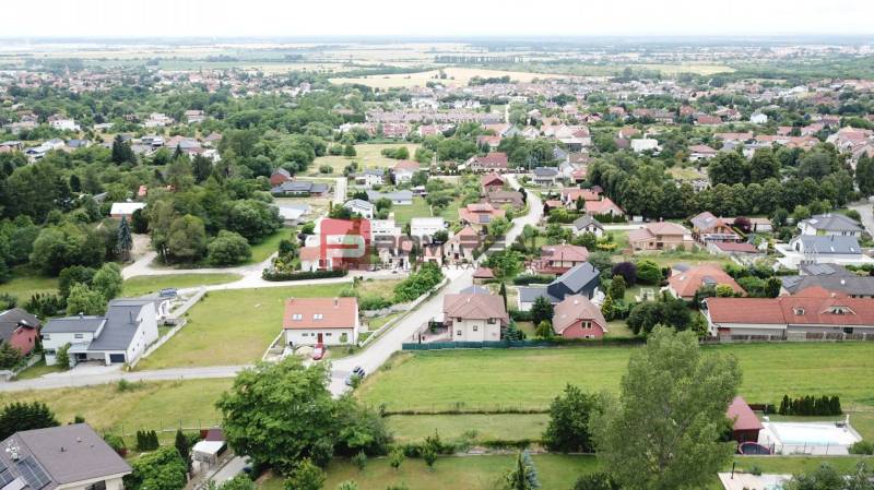Nádherný pozemok 632 m2 s výhľadom na Alpy Marianka - Letecký pohľad na domy a zeleň v obci Marianka na ulici Na Tálkoch. Pozemky - bývanie.