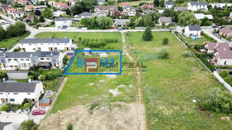 Rovinatý pozemok 800 m2 za dobrú cenu Marianka - Pozemky - bývanie v Marianke na Na Ovsisku, s výmerou 800 m², obklopené zeleňou a domami.