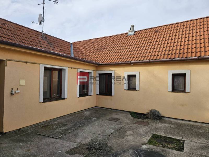 Rodinný dom na predaj Pezinok na skok od centra - Dvor rodinného domu na Slnečnej ulici v Pezinku s betónovou dlažbou a oranžovou fasádou.
