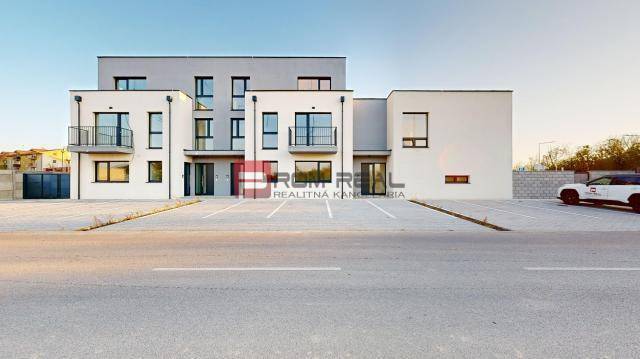 5 izbový RD - 128,33 m2 v novostavbe v Alžbetinom dvore - Budova na ulici Bottova, moderná architektúra, parkovisko a rodinný dom v pozadí.