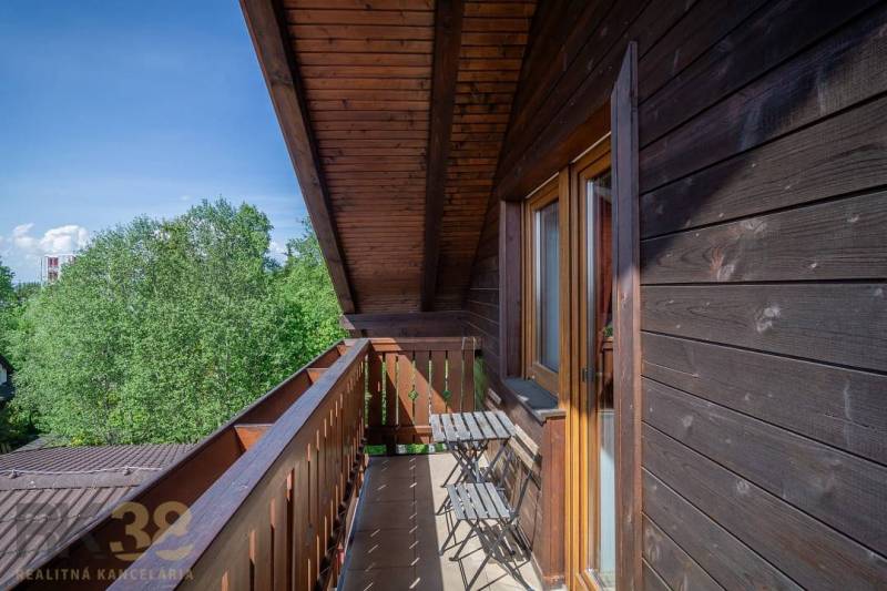 Znížená cena: priestranný apartmán s TOP polohou v Starom Smokovci - Balkón so stolom a stoličkami v Rekreačnom apartmáne s výhľadom na stromy vo Vysokých Tatrách.