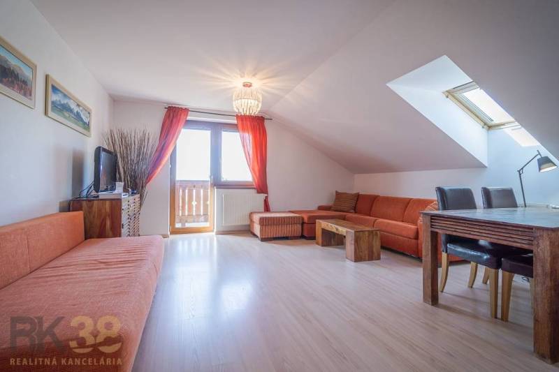 Znížená cena: priestranný apartmán s TOP polohou v Starom Smokovci - Rekreačný apartmán s oranžovou sedacou súpravou a jedálenským stolom pod strešným oknom.