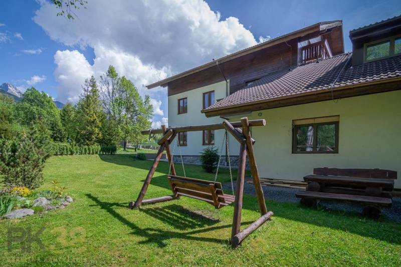 Znížená cena: priestranný apartmán s TOP polohou v Starom Smokovci - Záhrada s drevenou hojdačkou a lavičkou pri Rekreačnom apartmáne vo Vysokých Tatrách.