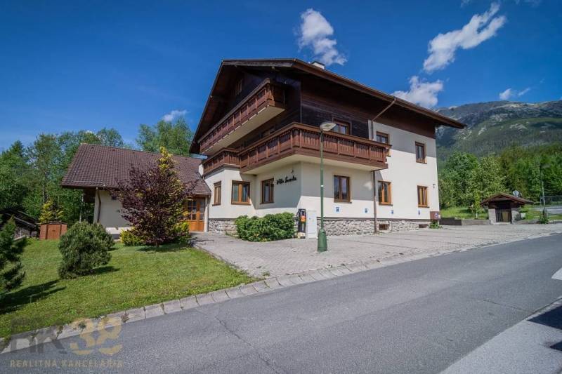 Znížená cena: priestranný apartmán s TOP polohou v Starom Smokovci - Rekreačný apartmán vo Vysokých Tatrách, obklopený zeleňou, modrá obloha, hory v pozadí.