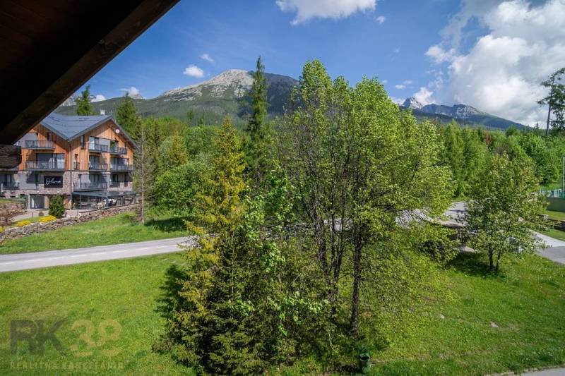Znížená cena: priestranný apartmán s TOP polohou v Starom Smokovci - Výhľad z rekreačného apartmánu vo Vysokých Tatrách, s horami a zelenými stromami.