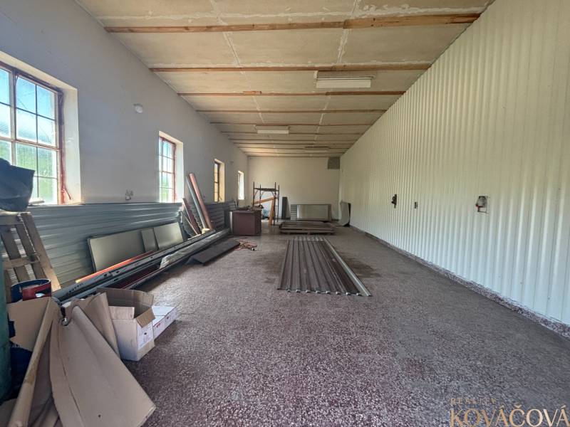 Na prenájom hala s pozemkom 4500 m² – Mníchova Lehota  - Interiér haly so skladovými materiálmi a oknami na jednej strane.
