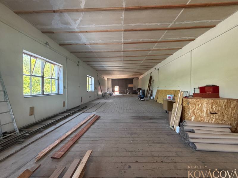 Na prenájom hala s pozemkom 4500 m² – Mníchova Lehota  - Interiér skladov a hál s drevenou podlahou, regálmi a stavebným materiálom.