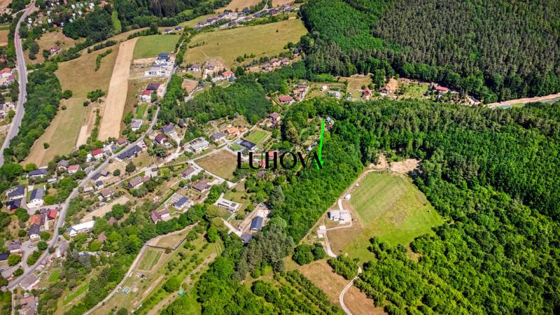 Pozemok s VEĽKÝM potenciálom_Vieska - Bezdedov (6441 m²) - Letecký pohľad na rekreačné pozemky obklopené lesmi a domami v Púchove, Vieska-Bezdedov.