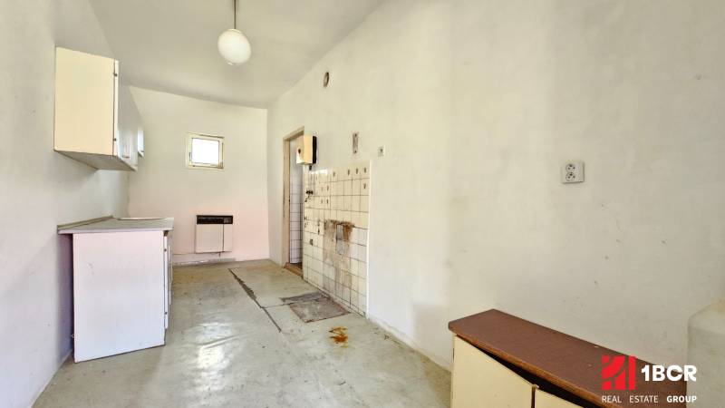 3 IZB ROD.DOM S VEĽKÝM POZEMKOM - KMEŤOVO, OKRES NOVÉ ZÁMKY - Staršia kuchyňa s jednoduchým zariadením, linoleum na podlahe. Pozemky - bývanie.