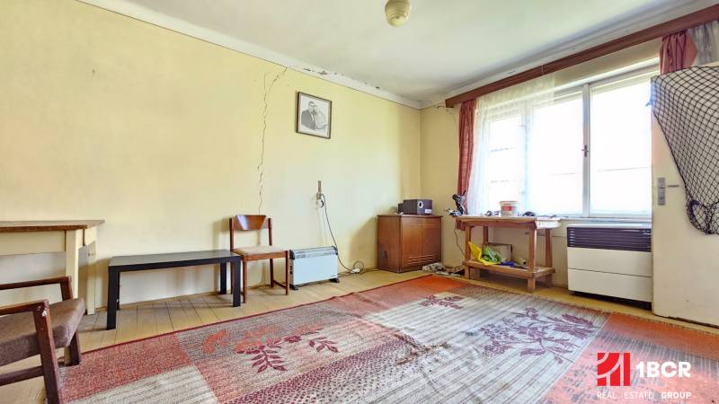 3 IZB ROD.DOM S VEĽKÝM POZEMKOM - KMEŤOVO, OKRES NOVÉ ZÁMKY - Izba s kobercami, starším nábytkom a oknami, praskliny na stenách. Pozemky - bývanie.