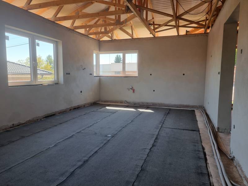 PREDAJ - 4 izbový s garážou - Nitra, Zobor  - Stavebný proces v rodinnom dome s odkrytými drevenými trámami a veľkými oknami.