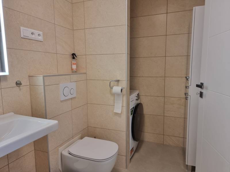 PRENÁJOM - Nový priestranný byt - Nitra, Centrum - Kúpeľňa s práčkou a toaletou v 2-izbovom byte s béžovými obkladmi.