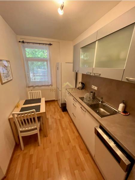 Predaj zariadený 2 izbový byt, Záhradnícka ulica,Bratislava II Ružinov - Kuchyňa v 2-izbovom byte s jedálenským stolom, bielymi skrinkami a spotrebičmi.