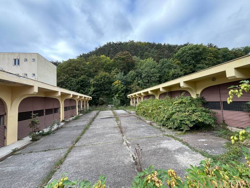 Na predaj pozemok 2269 m² so stavebným povolením na bytový dom,Trenčín - Opustený komplex budov v blízkosti lesa s náznakmi zanedbania.