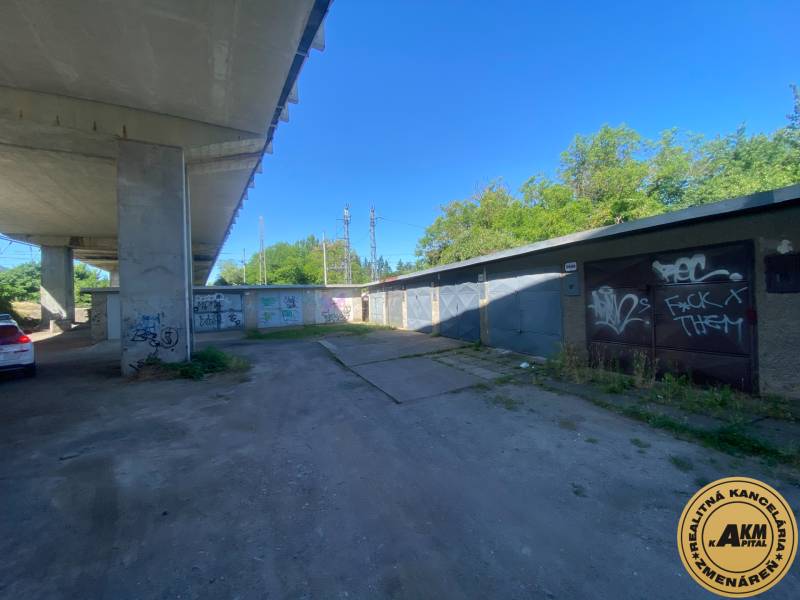 Garáž blízko Centra -  Zvolen na Predaj - Garáže v Zvolene pod mostom s grafitmi na stenách a zaparkovaným autom.