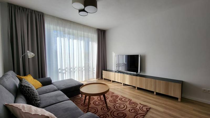 Nový priestranný 3iz. byt s klimatizáciou, balkónom a parkovaním. - Obývacia izba s pohovkou, stolíkom a televízorom v 3-izbovom byte.