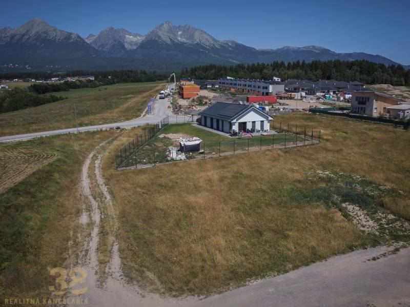 Stavebný pozemok v skvelej lokalite pod Tatrami - Pozemky na bývanie v Mlynici s výhľadom na Tatry, vidiecky dom a stavby v pozadí.