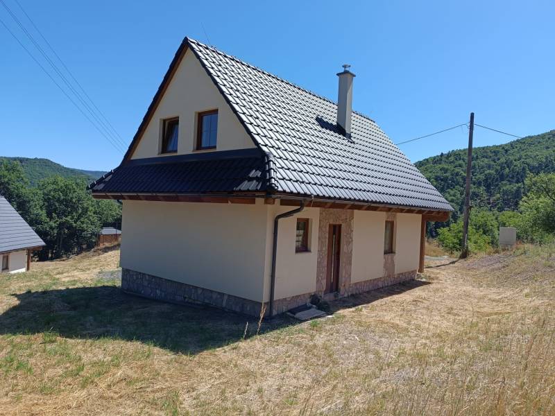 Na predaj chata novostavba  pri Novej Bani - Chata v Horných Hámroch s plechovou strechou a okolitou prírodou, pod modrou oblohou.