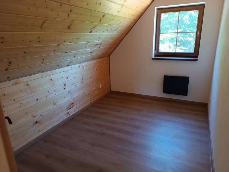 Na predaj chata novostavba  pri Novej Bani - Podkrovná izba s drevenými obkladmi a výhľadom z okna v chate.