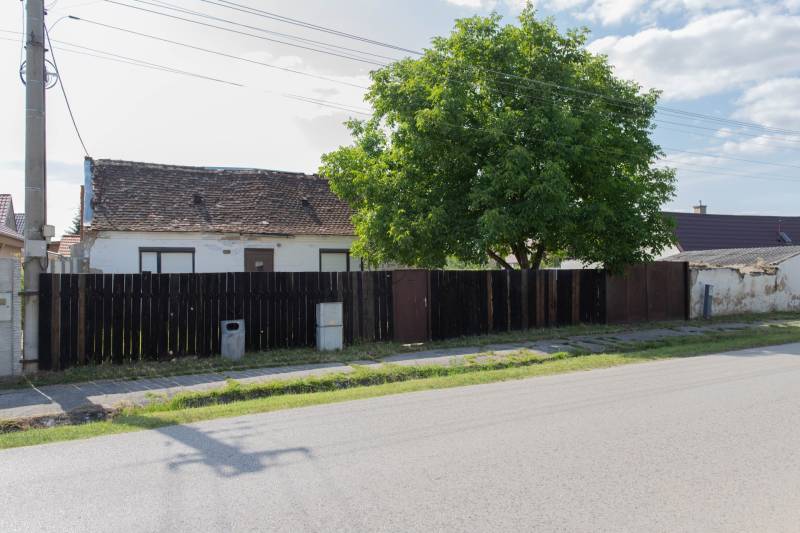 NA PREDAJ pekný slnečný stavebný pozemok na Športovej ulici v Gajaroch - Budova so starou strechou na Športovej ulici v Gajaroch, obklopená plotom. Pozemky - bývanie.