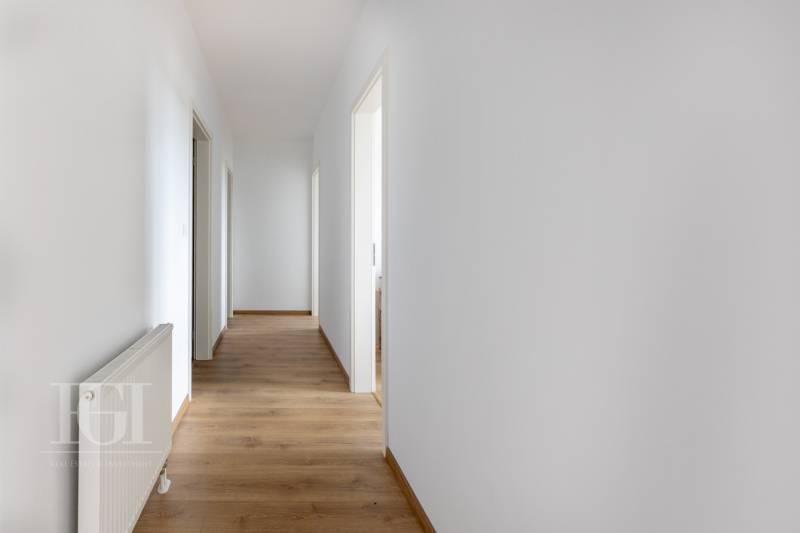 PRENAJOM | 3 Izbový byt + Loggia + Parking. PROMENADA LIVING PARK - Chodba v 3-izbovom byte s bielymi stenami a drevenou podlahou.