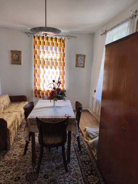 Rodinný dom Obsolovce - Jedáleň v rodinnom dome so stolom, stoličkami, kvetmi, kobercom a závesom.