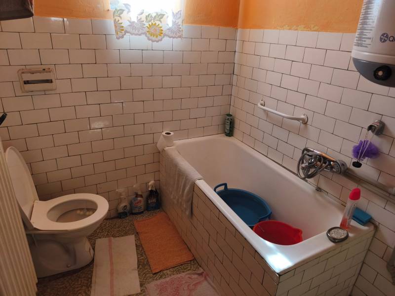 Rodinný dom Obsolovce - Kúpeľňa v rodinnom dome s bielymi obkladačkami, vaňou a toaletou.