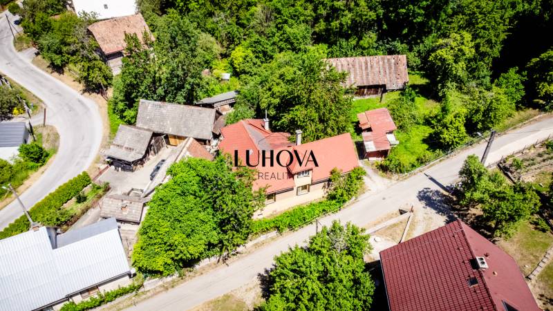 Starší rodinný dom – Ihrište_Púchov  - Letecký pohľad na rodinný dom v Púchove obklopený zeleňou a okolitými budovami.