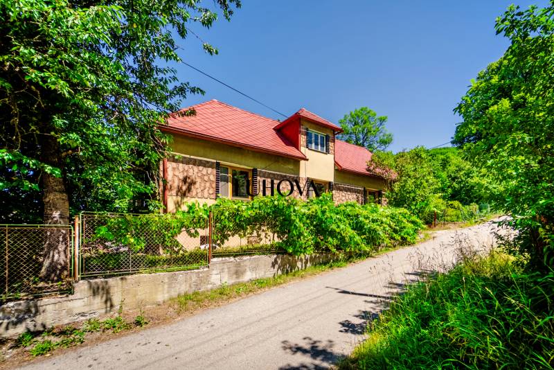 Starší rodinný dom – Ihrište_Púchov  - Rodinný dom na tichej ulici v Púchove s bujnou zeleňou a plotom.