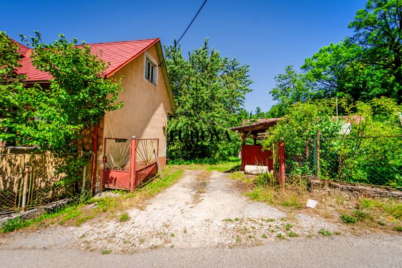 Starší rodinný dom – Ihrište_Púchov  - Rodinný dom na ulici v Púchove, obklopený zeleňou a prístupovou cestou.