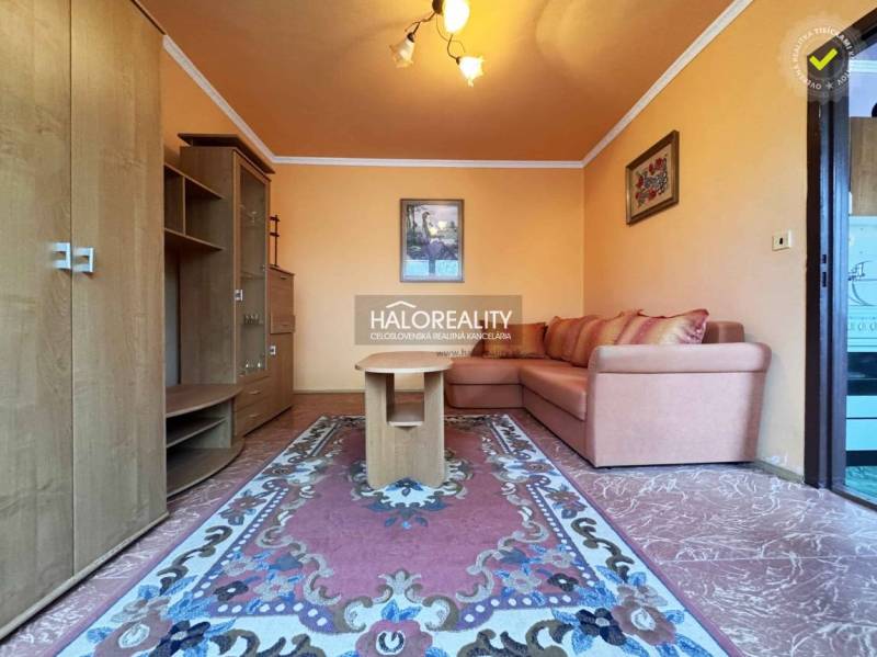 Predaj, jednoizbový byt Radvaň nad Dunajom, len 120 ... - Obývacia izba s oranžovými stenami, pohovkou a kobercom v 1-izbovom byte.