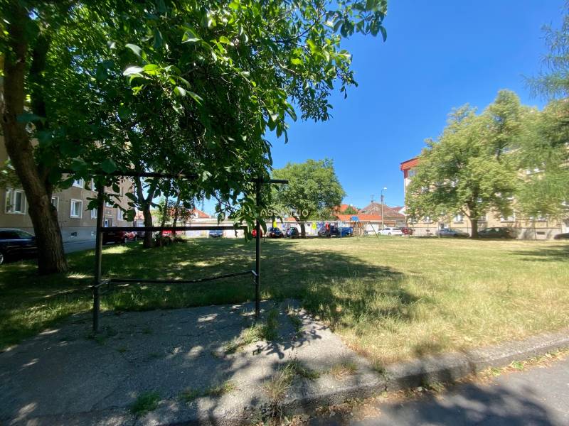 - PREDAJ - Priestranný 2i byt vo vyhľadávanej lokalite - Pokojná ulica Študentská v Trnave s bytovými domami a zeleným parkom v pozadí.