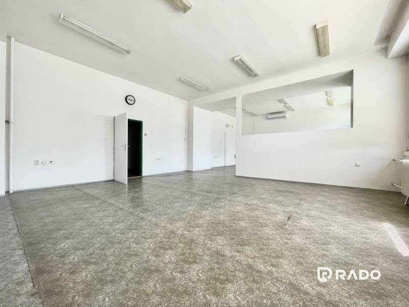 Kancelárie na prenájom 40m2, budova Fischer TireTech, TN - Priestranné kancelárie s bielymi stenami, podlaha z dlažby, dvere, hodiny na stene.