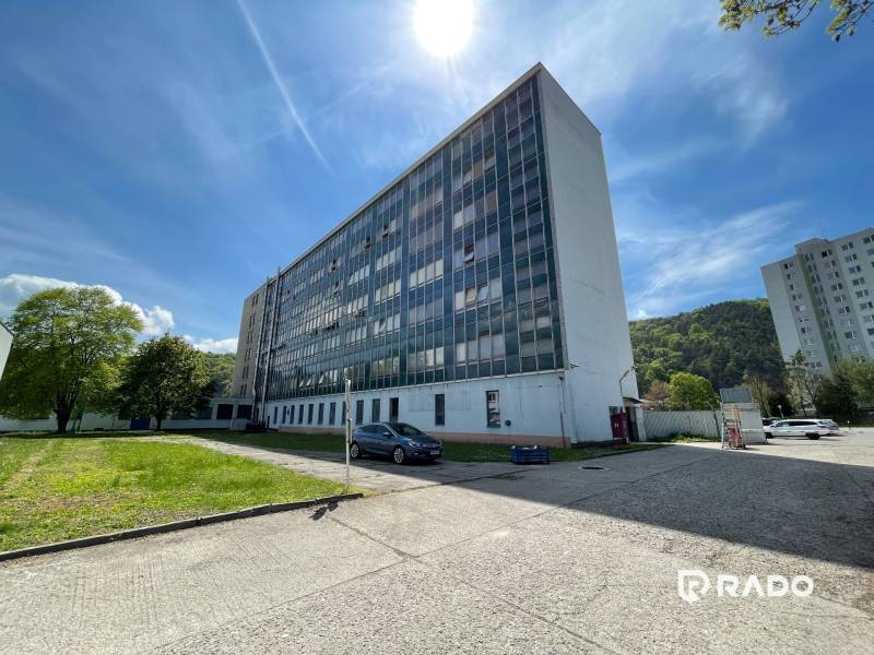 Kancelárie na prenájom 40m2, budova Fischer TireTech, TN - Kancelárie na ulici K výstavisku v Trenčíne, vedľa je trávnik a zaparkované auto.