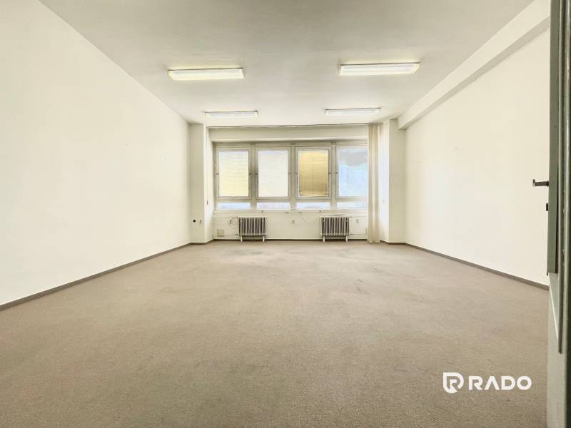 Kancelárie na prenájom 60m2, budova Fischer TireTech, TN - Prázdna kancelária s kobercovou podlahou a veľkým oknom, osvetlená stropnými lampami.