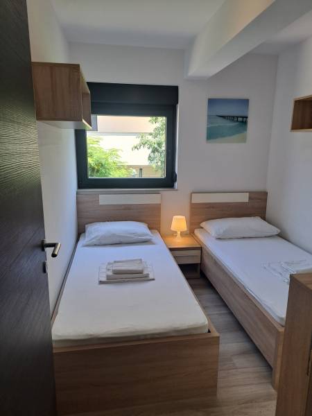 CHORVÁTSKO - Zariadený apartmán, 1. rad od mora - MANDRE, ostrov PAG - Izba v 3-izbovom byte s dvoma posteľami, nočným stolíkom a oknom s výhľadom.