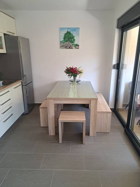 CHORVÁTSKO - Zariadený apartmán, 1. rad od mora - MANDRE, ostrov PAG - Jedálenský kút v 3-izbovom byte s dreveným stolom, kvetmi a obrazom stromu na stene.