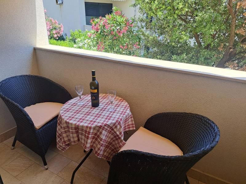 CHORVÁTSKO - Zariadený apartmán, 1. rad od mora - MANDRE, ostrov PAG - Balkón 3-izbového bytu s dvojicou stoličiek a stolom s vínom a pohármi.