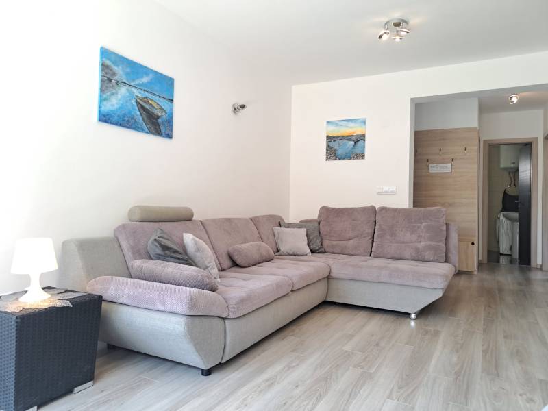 CHORVÁTSKO - Zariadený apartmán, 1. rad od mora - MANDRE, ostrov PAG - Priestor 3-izbového bytu s pohodlnou sivou sedačkou a svetlým dreveným podlahovým dekorom.