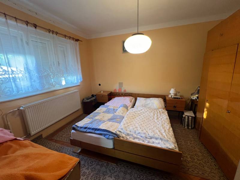 RD Drahovce - Spálňa v rodinnom dome s dvoma posteľami, skriňou a kobercom.